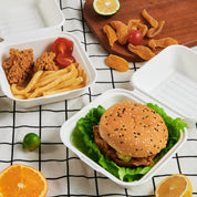 ECOLipak disposable take - out food containers, perfect for packing a burger, fried chicken, fries, and fresh fruits.
