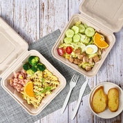 Two ECOLipak eco-friendly takeout containers with pasta, shrimp, and broccoli, plus a fresh salad, orange slice, and two pieces of garlic bread.