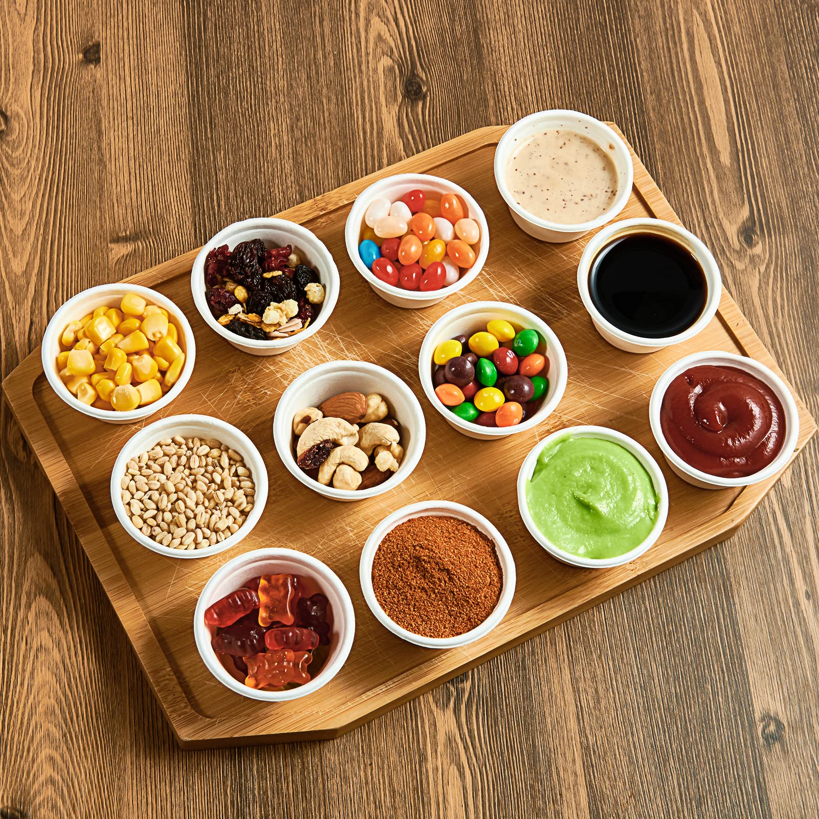 A wooden tray holds various small ECOlipak disposable eco - friendly paper cups filled with different foods and condiments, such as corn kernels, dried fruits, nuts, candies, sauces, and spices.